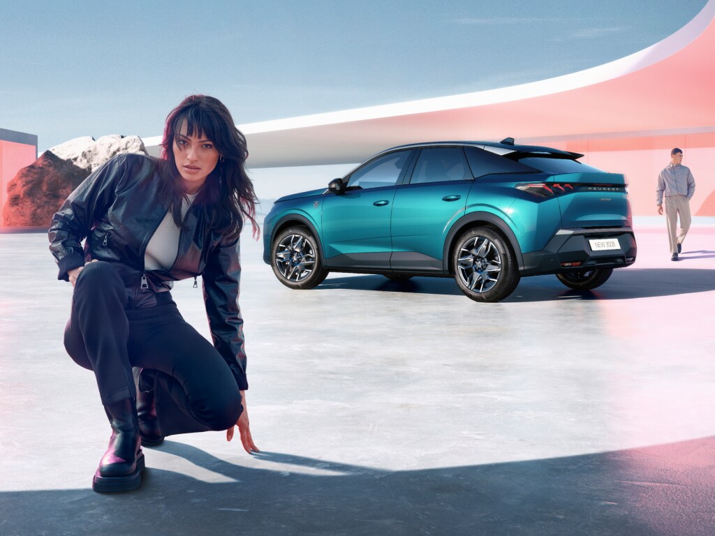 Vrouw knielt naast nieuwe PEUGEOT 3008 Hybrid met achteraanzicht